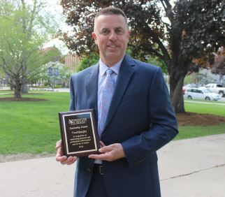 Daniel Matejka poses with plaque recognizing his being named an outstanding alum