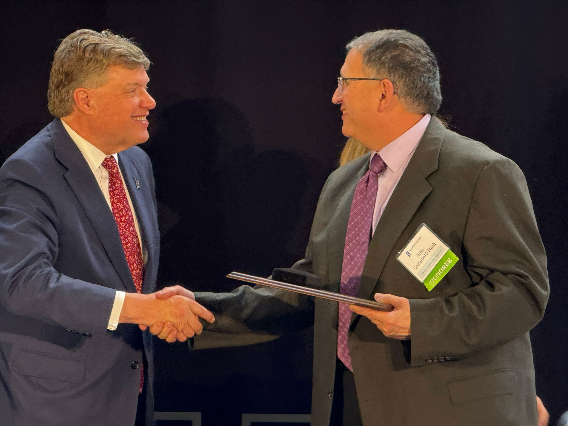 Minnesota State Chancellor Scott Olson (left) shakes hands with Southeast Band Instrument Repair instructor John Huth, after Huth was honored as Educator of the Year.
