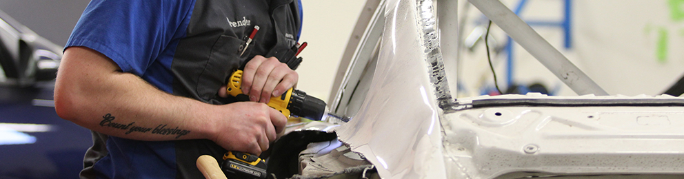 Close-up of a worker drilling on a piece of automotive sheet metal