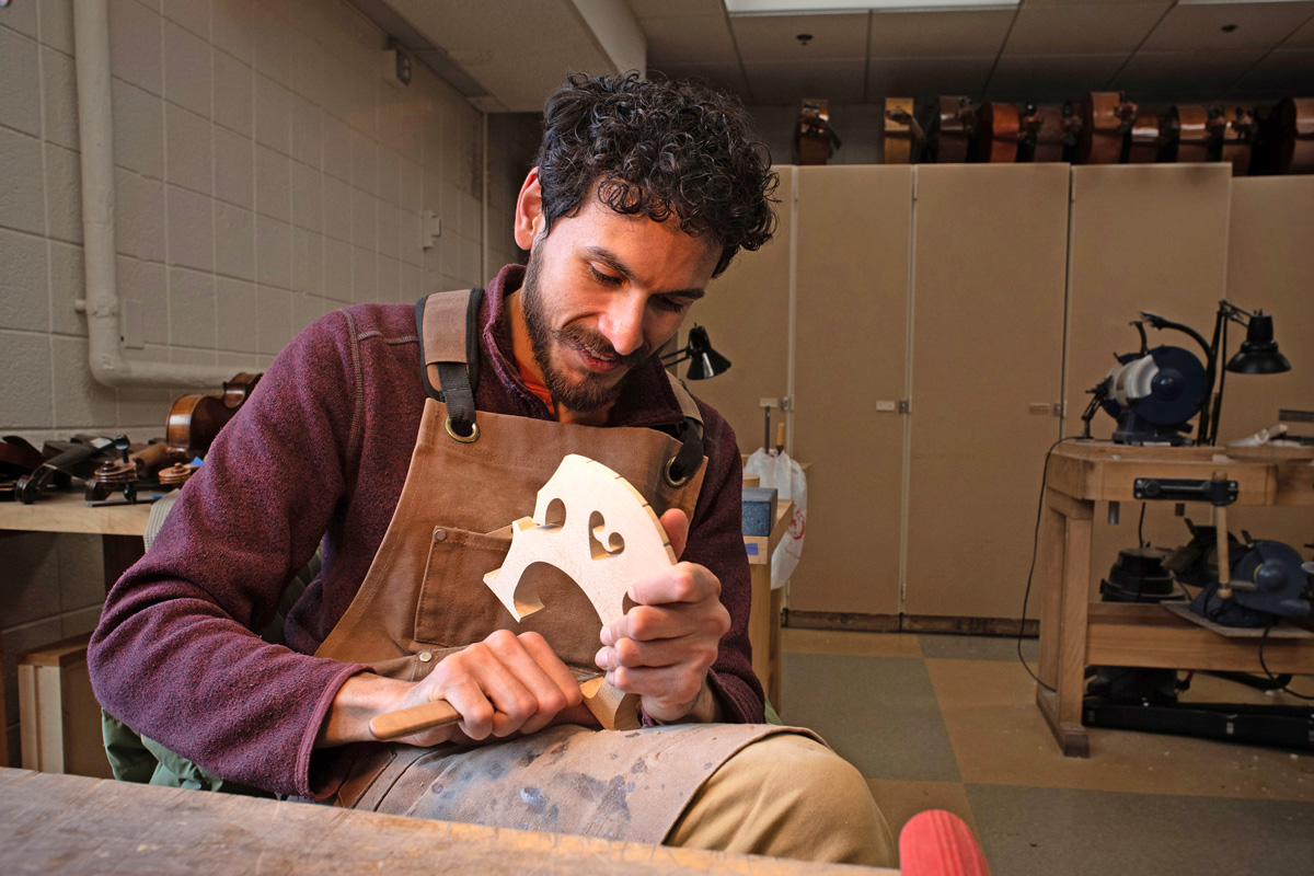 Southeast student Ethan Balakrishnan works on the bridge of the instrument he is building.