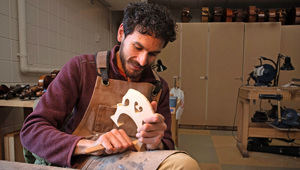 Southeast student Ethan Balakrishnan works on the bridge of the instrument he is building.