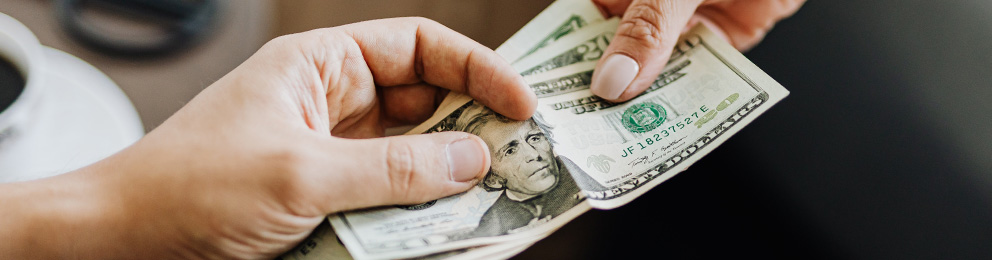 $20 bills being handed from one person to another