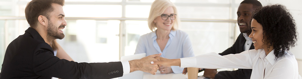 Smiling people shaking hands at a meeting table
