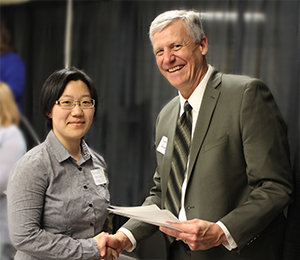 Gentleman holding papers shanking hands with a lady