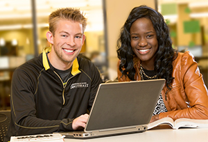 Two students smiling with a laptop