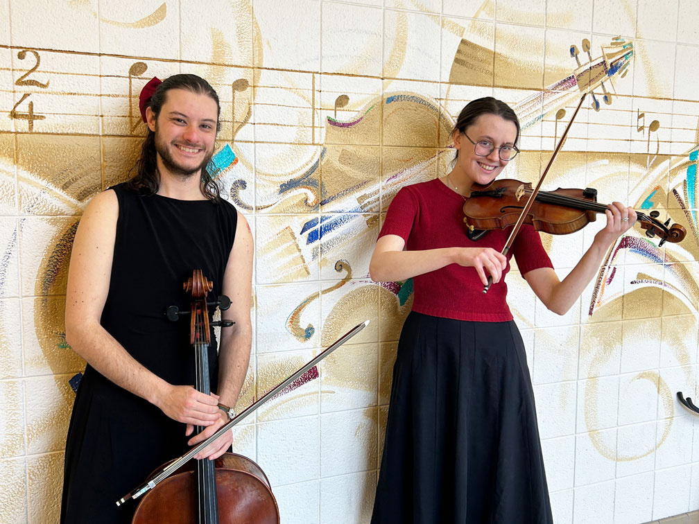 The duet of Tuney Loons poses for a picture with cello player holding the instrument in front of him and the violinist pretending to play